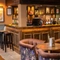 The bar at the Grapes, with some stools next to it and a seating area in front of it.