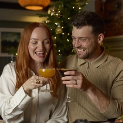 An image showing 2 people sat at a table within the interior restaurant seating area celebrating with a cheers while enjoying Festive Picky Bits at a Chef & Brewer venue.
