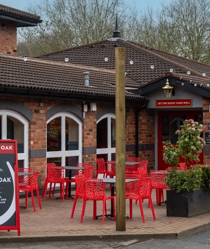 The exterior facade and seating area of the Cuckoo Oak, with planter boxes beside the tables and string lights above.