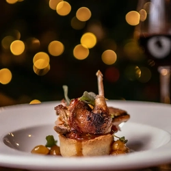 A roasted partridge, served with vegteables, in a bowl.