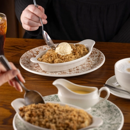 Plates of Apple Crumble on a wooden table of a pub