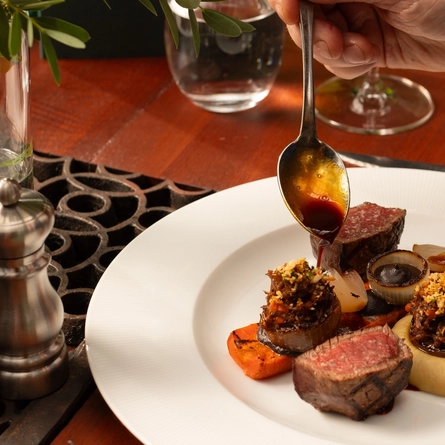 An image of a customer dressing a plated dish with sauce within the interior restaurant and seating area at The Ubiquitous Chip.