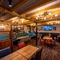 An interior restaurant seating area at the Old School House, with upholstered chairs and booth seating, and a TV and framed artwork on the wall.
