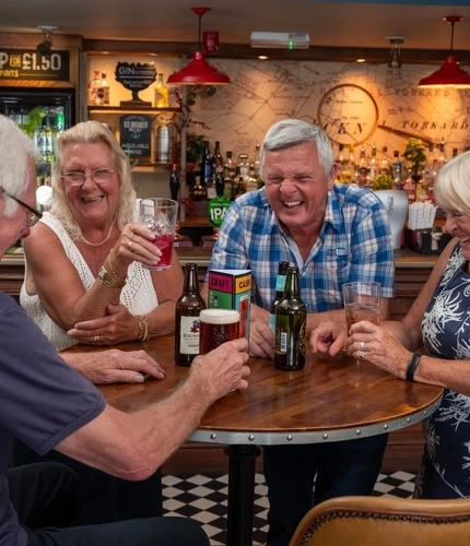 a group of people sitting at a table of a Greene King pub drinking beers