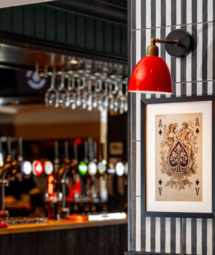 A close up view of one of the interior restaurant tables in the bar area of The Bramford Arms, with menus and condiments in a small wooden box on the table, and a framed piece of art on the wall above it.
