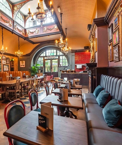 The interior restaurant seating area with tables, chairs, cushioned seating, seating booths, exposed brickwork and ornate chandelier lighting at The Duke Of Sussex.