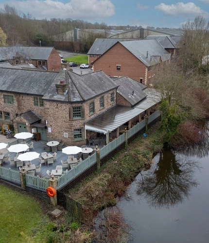 An aerial view of the exterior facade and beer garden seating area of The Malthouse Farm, and the canal that runs alongside the pub.
