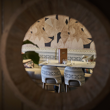 An image of the interior restaurant seating area viewed through a circular cut out in the wooden panelling at The Foundry Bell.