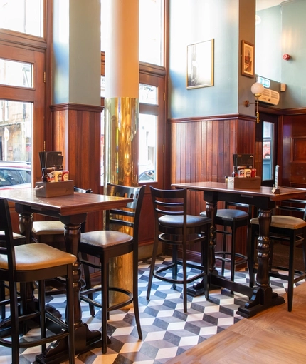 The interior restaurant seating area at the Rhoderick Dhu in Glasgow; with wood panelled walls, upholstered booth seating, and a TV on the wall.