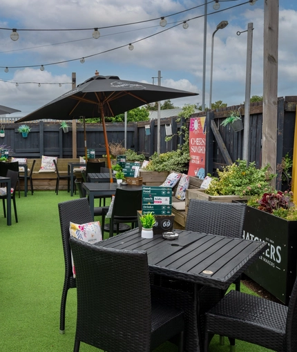 The exterior beer garden seating area at The Royal Oak; with shade umbrellas, and string lights overhead.