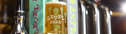 A pint of Level Head IPA in front of a Level Head pump on a bar.