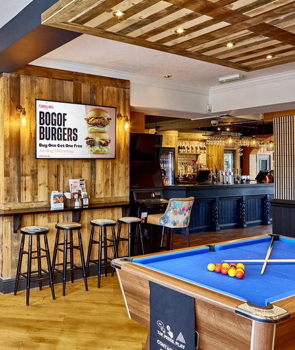 The dartboard, pool table, games machine and seating area inside The Fox and Crown.