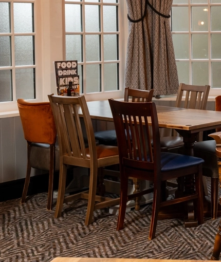 An interior restaurant seating area at The Railway, with three tables placed next to a large bay window.