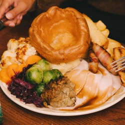 An image of 2 customers sat at a table enjoying festive main dishes and various drinks within the interior restaurant seating area at a Pub & Carvery venue.