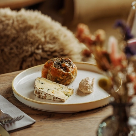 An advertising image of a Cheese Night dish showing a selection of cheeses within the interior restaurant and seating area at The Foundry Bell.