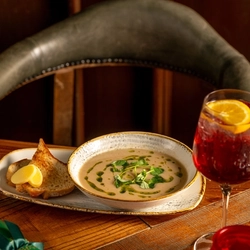 A wooden table holding a bowl of soup.