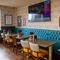 The interior restaurant seating area at The Kittoch with a long, upholstered booth seat, a TV on the wall above it, and framed artwork on the walls.
