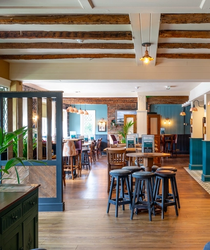 The bar and interior restaurant seating area at The Walkford, with wooden beams on the ceiling.