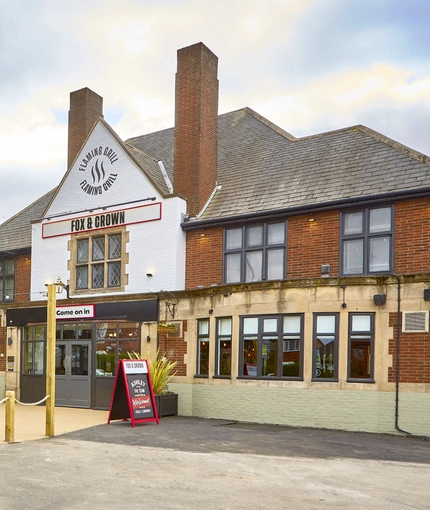 The exterior facade, signage and beer garden seating area at The Fox and Crown in Sutton-In-Ashfield.