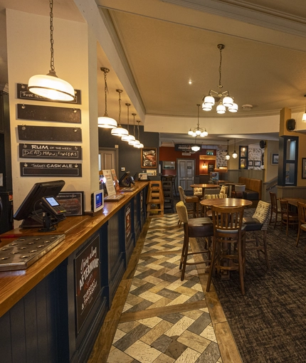 Interior dining area of a pub with a bar and a TV.