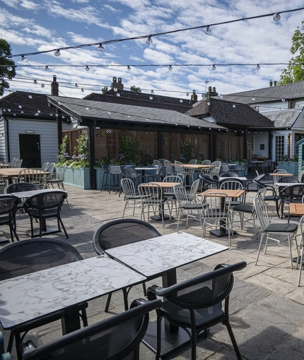 The exterior beer garden seating area with undercover and hut seating area at The Bell.