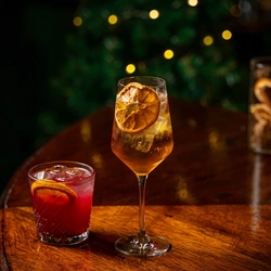 Two cocktail type drinks on a bar.  One in a low ball tumbler and the other is in a stemmed glass.
