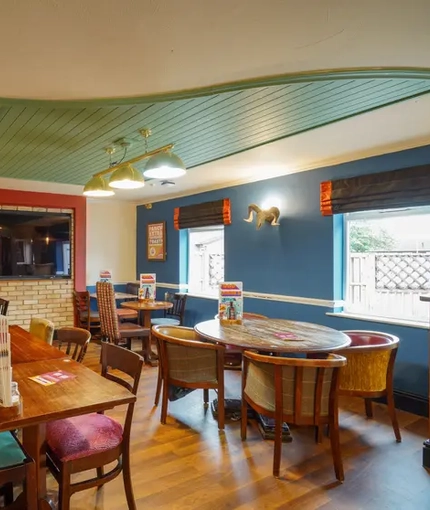 Interior dining area of a pub with a TV and a dartboard.