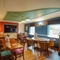 Interior dining area of a pub with a TV and a dartboard.