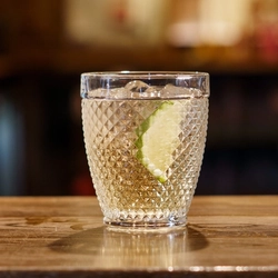 A cocktail in a lowball tumbler glass on a bar.