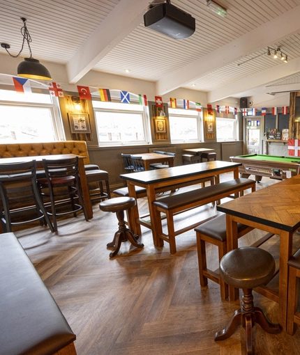 Interior dining area of a pub with a pool table and a TV.