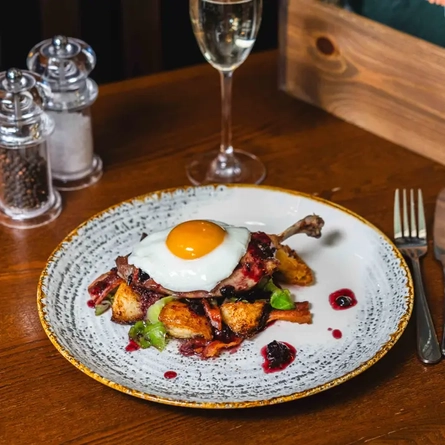 Plate of food set on the table with cutlery, menus and a glass of fizz