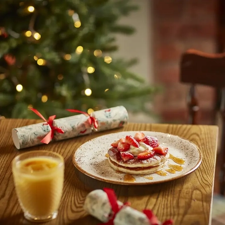 A plate of pancakes, served with strawberries, on a table.