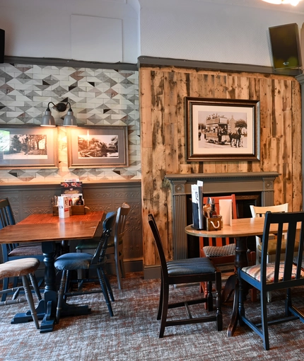 Interior dining area of a pub with a TV playing tennis and a fireplace.