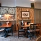 Interior dining area of a pub with a TV playing tennis and a fireplace.
