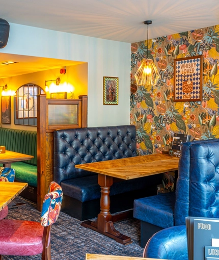 An interior restaurant seating area at the Counting House, with upholstered booth seats, and framed artwork on the walls.