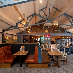 The interior restaurant seating area of The Stanley Ferry, with upholstered booth seating and a TV on the wall.