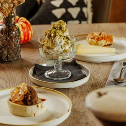 An advertising image of 2 Game Night desserts and a plated cheese dish with a coffee cocktail style drink within the interior restaurant and seating area at The Foundry Bell.