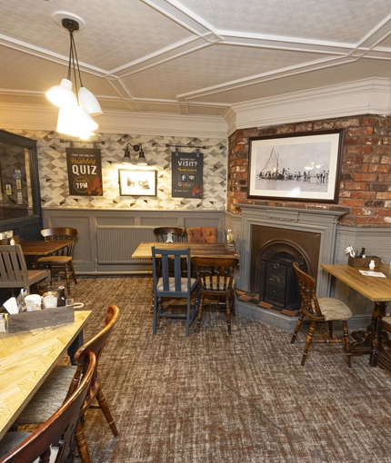 Interior dining area of a pub with a fireplace.