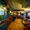 The upper floor wood panelled bar and interior restaurant seating area at The Globe; with parquet flooring, and TVs on the walls.