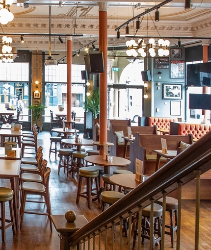 A view from the top of a staircase, looking down at the bar and interior restaurant seating area of Coopers in Glasgow.