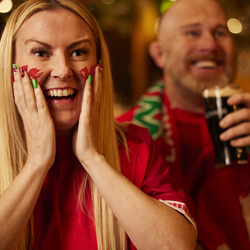 An image of a woman wearing a sport team shirt, watching a sporting event.