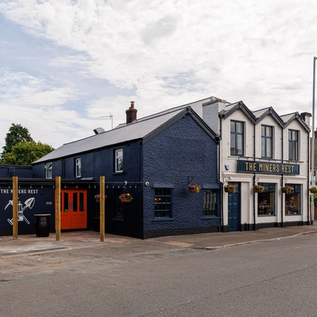 The exterior facade of the venue with hanging baskets and venue signage at The Miners Rest.