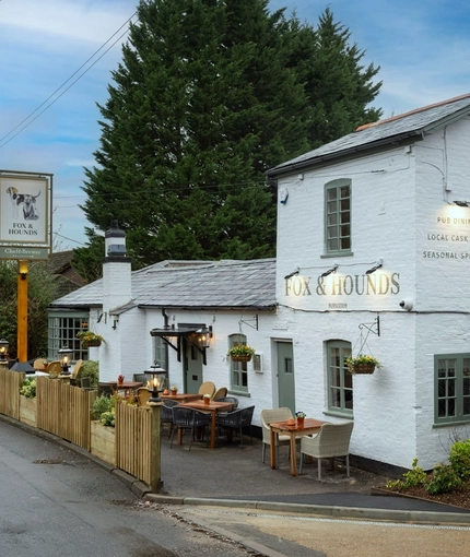 The exterior facade, signage, and seating area of The Fox & Hounds in Bursledon, with flower baskets hanging on the wall.