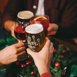 A group of people seated at a festive decorated table, holding drinks in a toast.