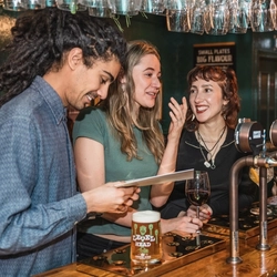 A group of people stood at a bar.