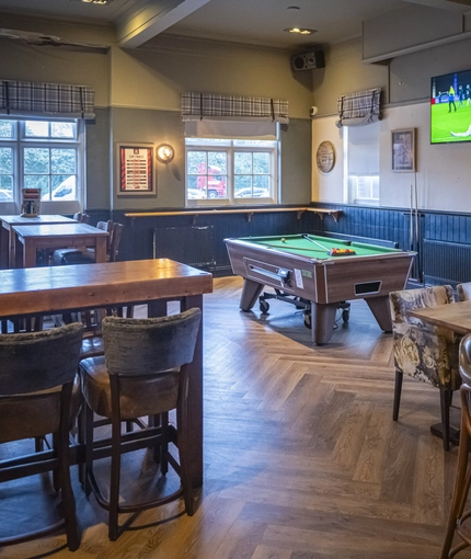 Interior dining area of a pub with a TV and a pool table.
