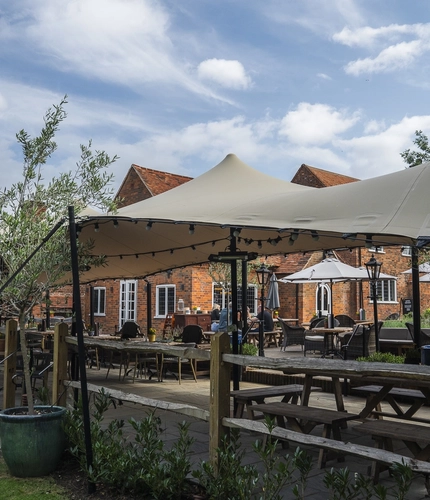 The exterior beer garden seating area with partial undercover section and the venue in the background at The Crown.