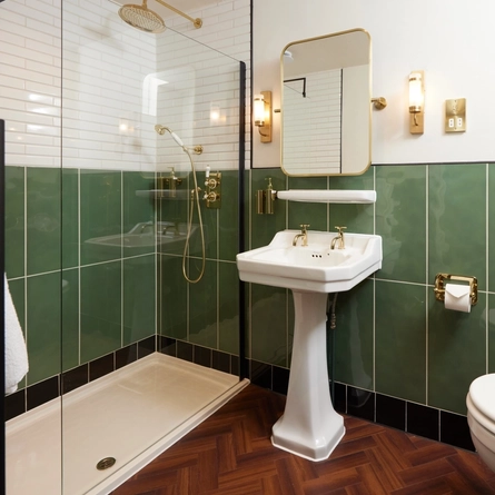 A hotel room ensuite with mirror, ornate sink, shower and WC in one of the bedrooms at The Dog and Partridge.