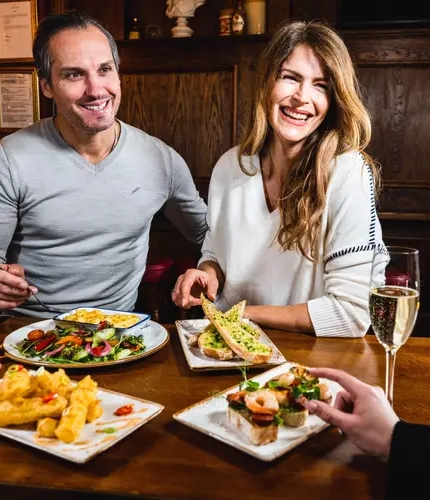 Two guests enjoying various plates of starters in a pub