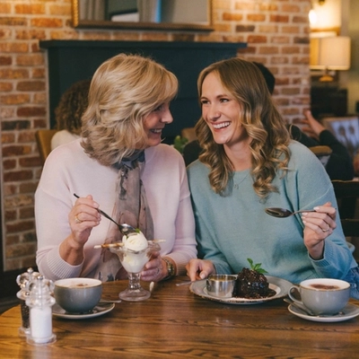 A lifestyle image of 2 ladies enjoying Mothers Day dessert dishes and hot drinks within the interior restaurant seating area at a Pub & Grill venue.